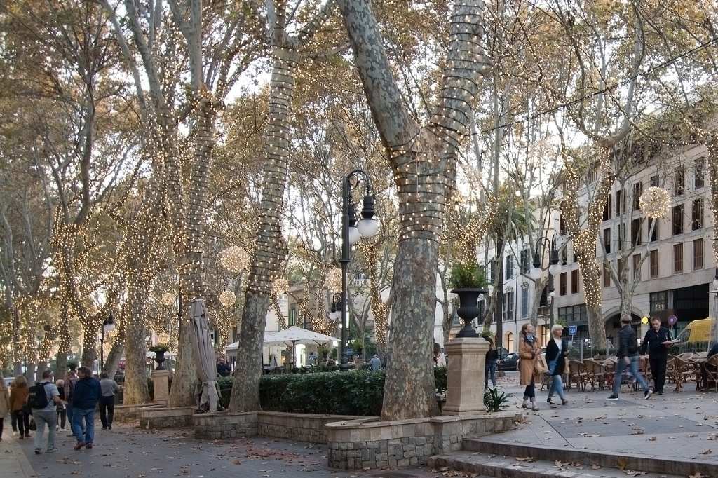 Menschen gehen in Palma de Mallorca eine mit Weihnachtsbeleuchtung geschmückte Straße entlang