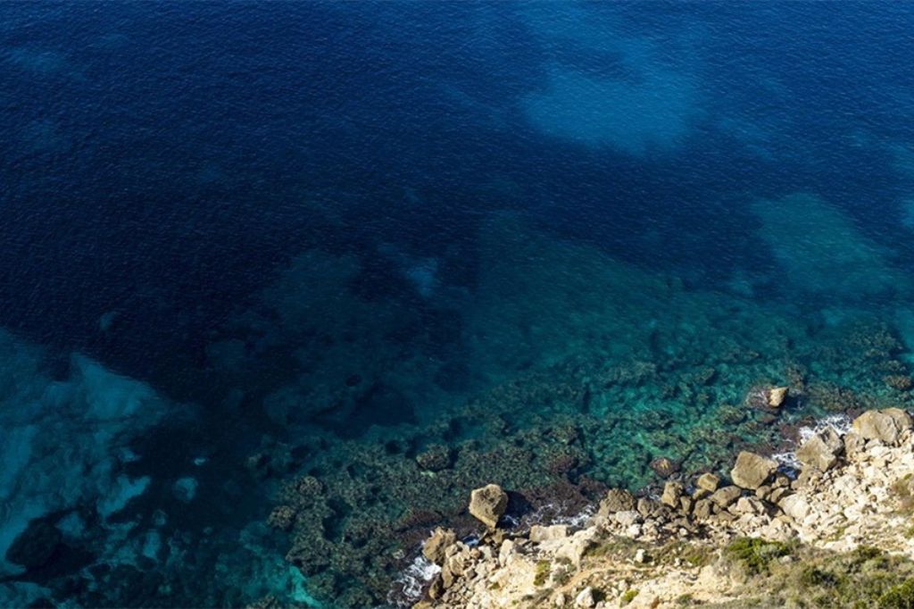 Klares blaues Meer und Klippen in Badia Grande